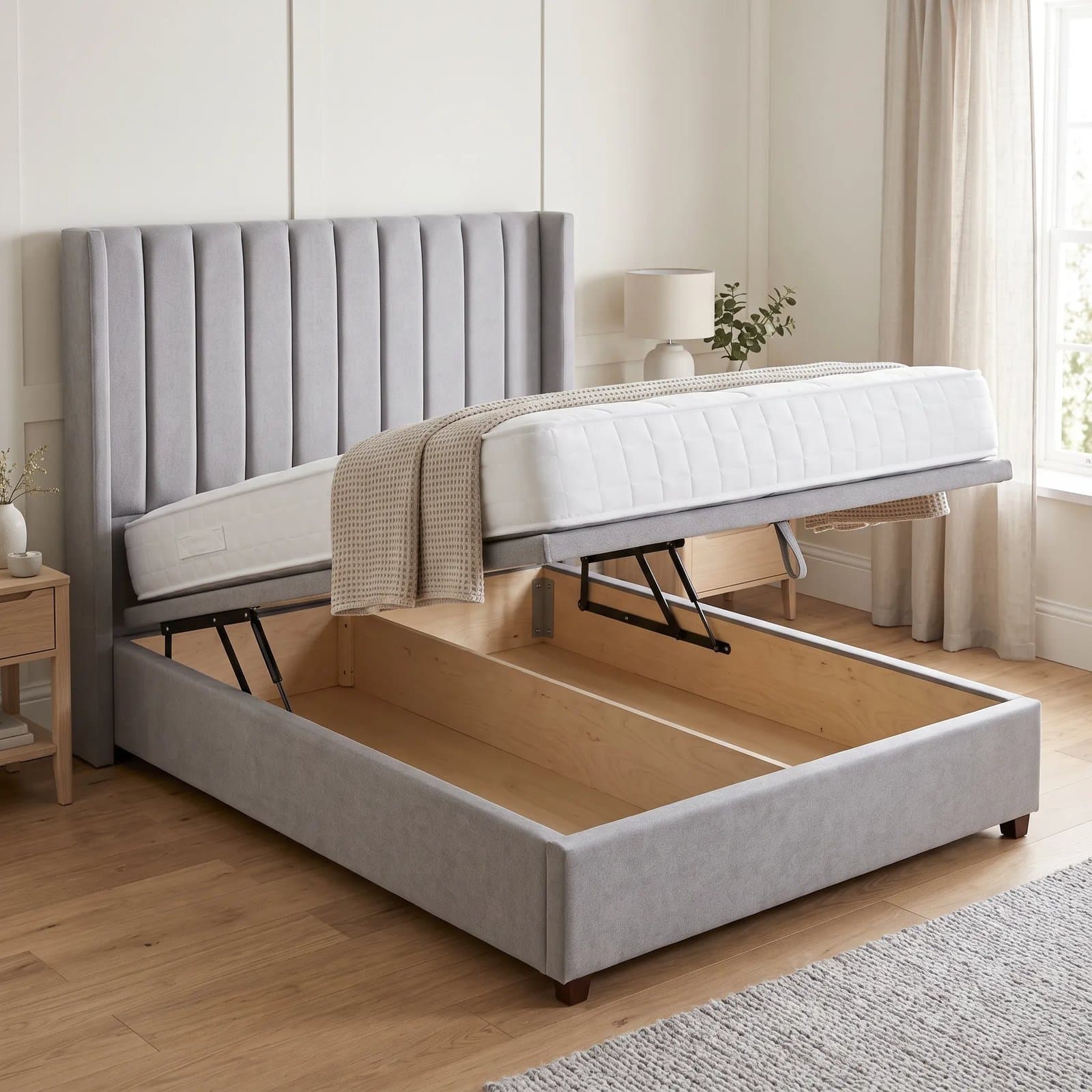 Rome ottoman storage bed with a winged headboard with vertical fluted panelling, base raised to show the full-length storage
